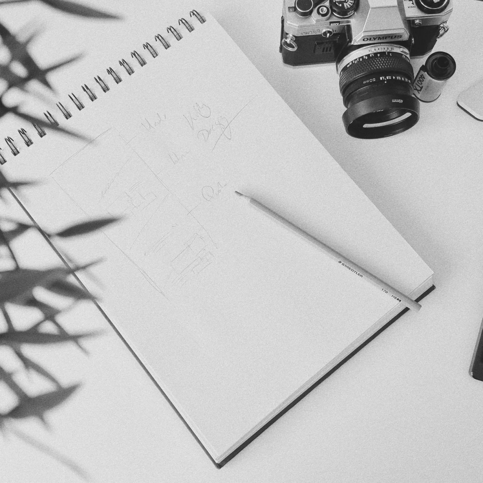 Sketchbook with website wireframes, a pencil and an Olympus film camera